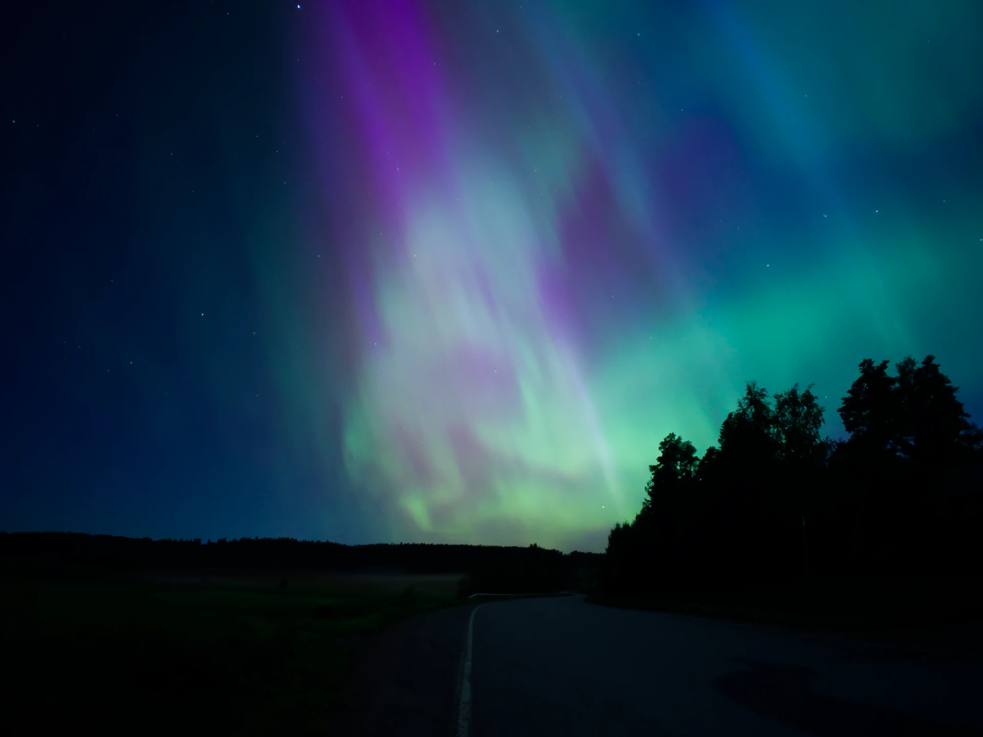 Revontulet yötaivaalla Etelä-Suomessa, pitkä valotus tuo esiin vihreät ja punertavat sävyt.